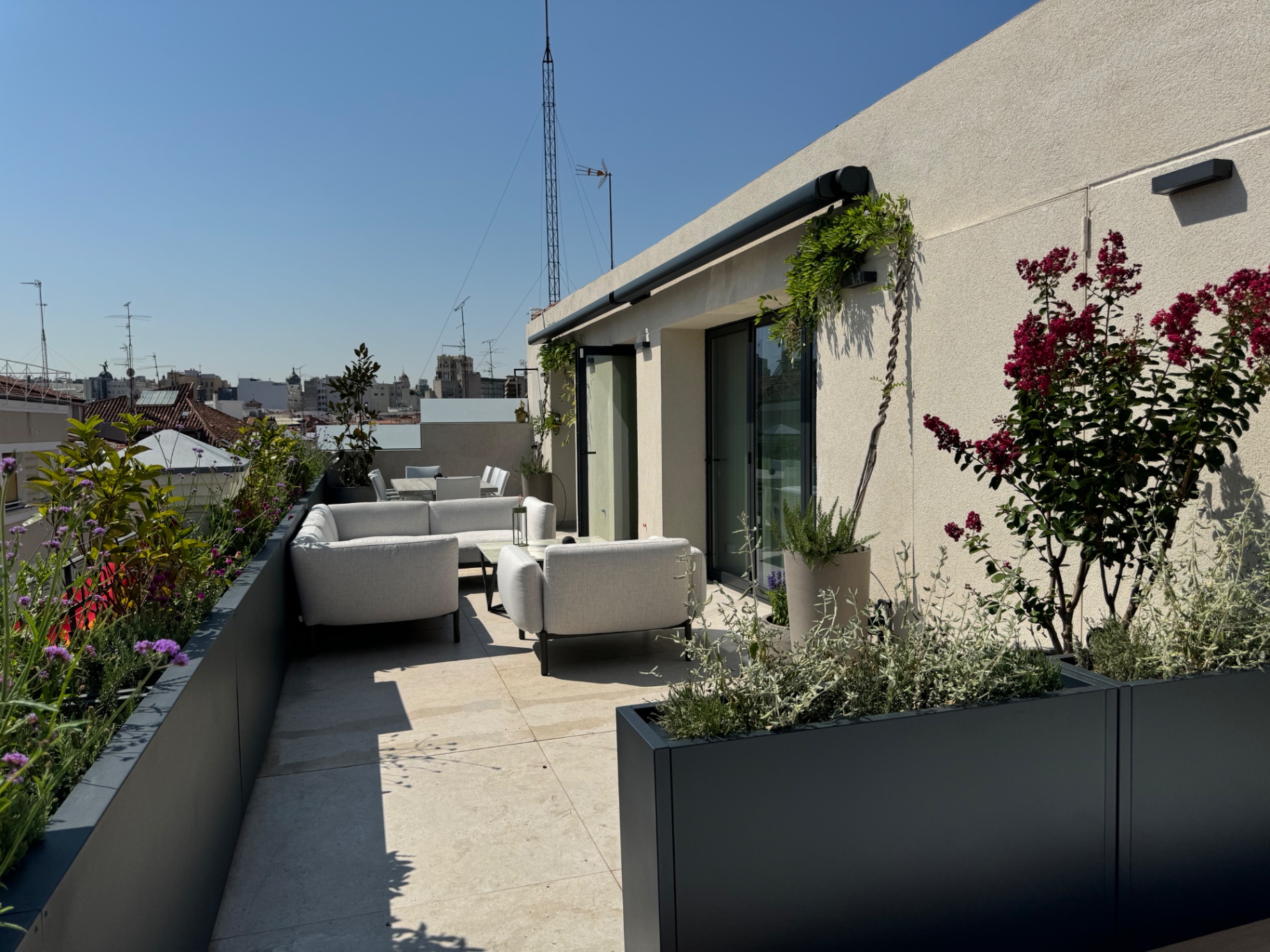 Recorrido largo de la terraza con zona de estar y vegetación mediterránea por capas